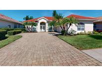 Charming home featuring a well-manicured front yard, brick driveway, and a tile roof at 421 Marsh Creek Rd, Venice, FL 34292