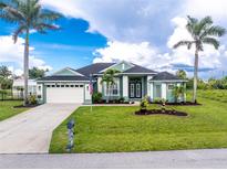 Charming single-story home with a well-manicured lawn, palm trees, and a two car garage at 9954 Audrey St, Port Charlotte, FL 33981