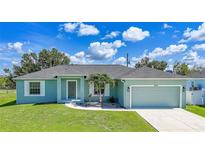 Charming single-story home featuring a well-manicured lawn and an attached two-car garage at 12112 Helios Ave, Port Charlotte, FL 33981