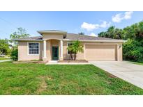 Inviting single-story home with a well-manicured lawn and a two-car garage in a sunny, tropical setting at 1693 Jagust Rd, North Port, FL 34288