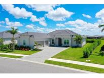 Beautiful home featuring a meticulously landscaped yard, gray roof, and charming entryway at 17336 Sandpearl Rd, Venice, FL 34293