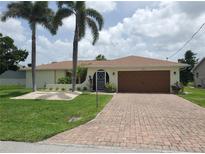 Charming single Gathering home with a two-car garage, beautiful lawn, and mature palm trees at 2220 Broad Ranch Dr, Port Charlotte, FL 33948