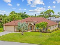 Stunning single-story home with a well-manicured lawn and beautiful landscaping, including several palm trees at 37 Marker Rd, Rotonda West, FL 33947