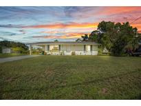 Charming single-story home featuring a well-maintained lawn and inviting curb appeal at sunset at 769 Crestview Nw Cir, Port Charlotte, FL 33948