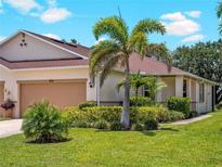 Charming home featuring a well-manicured lawn, lush landscaping, and a two-car garage at 8814 Tuscany Isles Dr, Punta Gorda, FL 33950