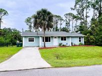 Charming single-story home with a well-maintained lawn, palm tree, and a long concrete driveway at 15090 Rebecca Ave, Port Charlotte, FL 33953