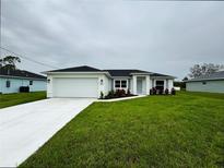 Charming single-story home featuring a well-manicured lawn, a two-car garage, and colorful landscaping at 8917 Sawyer Cir, North Port, FL 34288