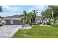 Charming single-story home featuring a well-maintained lawn and two-car garage and attractive landscaping at 18483 Hottelet Cir, Port Charlotte, FL 33948