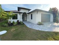 Modern single-story home with gray paver driveway and landscaping at 124 Hercules Dr, Rotonda West, FL 33947