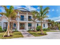 Elegant two-story home featuring a charming front porch, wooden accents, and lush landscaping with mature palm trees at 10009 Gasparilla Pass Blvd, Boca Grande, FL 33921