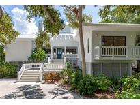 Inviting coastal home featuring a light exterior paint, well-kept landscaping, and a blue front door at 6895 Manasota Key Rd, Englewood, FL 34223