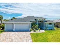 Two-car garage, gray house with teal front door and landscaping at 779 Boundary Blvd, Rotonda West, FL 33947