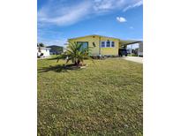 Yellow mobile home with palm tree and lawn at 6276 Oriole Blvd, Englewood, FL 34224