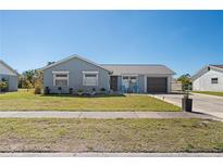 Charming one-story home with blue exterior, well-maintained lawn, and inviting front porch area at 13525 Dibella Ave, Port Charlotte, FL 33981