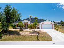 Single-story home with a two-car garage and landscaped yard at 9660 Miami Cir, Port Charlotte, FL 33981