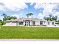 White one-story home with brown accents, screened porch, and landscaped lawn at 5039 Parker St, Port Charlotte, FL 33981