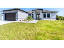 Modern house exterior with a two-car garage and landscaped yard at 11042 Carnegie Ave, Englewood, FL 34224
