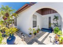 Inviting front entry with arched walkway, mature landscaping, and charming decor at 604 Foxwood Blvd, Englewood, FL 34223