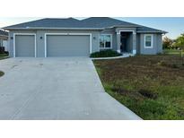 Three-car garage gray house with a large front yard at 48 Long Meadow Ln, Rotonda West, FL 33947
