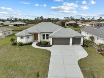Beautiful one story home featuring a grey roof, a two car garage, and a well manicured lawn at 256 Mariner Ln, Rotonda West, AK 33947
