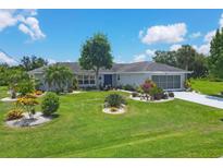 Single-story home with well-manicured lawn, landscaped gardens and a blue door at 2516 Dixon Ter, Port Charlotte, FL 33981