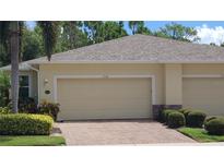 Tan house exterior with double garage and nicely landscaped front yard at 13524 Abercrombie Dr, Englewood, FL 34223