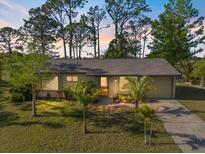 Charming single-story home with a well-manicured lawn and mature trees under a beautiful sky at 6517 Kenwood Dr, North Port, FL 34287