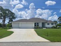 Charming single-story home with a three-car garage, lush lawn, and a well-maintained landscape at 261 Broadmoor Ln, Rotonda West, FL 33947