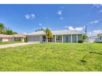 Ranch-style home with gray exterior, screened porch, and large yard at 10168 Willowood Ave, Englewood, FL 34224