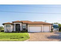 Charming single-story home with a well-manicured lawn and a three-car garage on a brick driveway at 15964 Viscount Cir, Port Charlotte, FL 33981