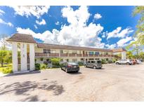 Low-rise condo building with ample parking and well-maintained landscaping on a bright, sunny day at 3 Quails Run Blvd # 8, Englewood, FL 34223