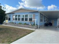 Light blue single-wide manufactured home with covered carport and landscaped yard at 6432 Keena Ct, North Port, FL 34287