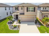 Charming two-story home with a manicured lawn, stone accents, and a spacious two-car garage at 7537 Pool Compass Loop, Wesley Chapel, FL 33545