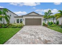 Single-story home with a brown garage door, landscaping, and a brick paver driveway at 1352 Sunset Preserve Way, Port Charlotte, FL 33953