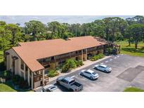 Aerial view of condo building with parking and lush landscaping at 8 Quails Run Blvd # 10, Englewood, FL 34223