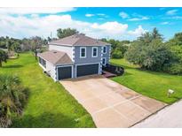 Two-story home with an attached two-car garage, long driveway, and lush green lawn at 13401 Galveston Ave, Port Charlotte, FL 33981