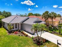 Charming home features a well-manicured lawn, colorful flowerbeds, and tall palm trees, creating curb appeal at 3359 Osprey Ln, Port Charlotte, FL 33953