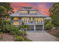 Attractive two-story home with gray siding, metal roof, and a paved driveway at 22 Seawatch Dr, Boca Grande, FL 33921