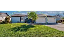 Front view of a light blue house with a palm tree and two-car garage at 612 Deerwood Ave # 169, Englewood, FL 34223