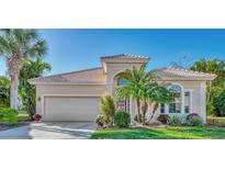 Tan one-story house with a red door, two-car garage, and lush landscaping at 2803 Sawgrass Ct, Port Charlotte, FL 33953