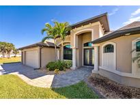 Inviting home featuring a well-manicured lawn, a two-car garage, and an elegant arched entryway framed by stately columns at 849 Rotonda Cir, Rotonda West, FL 33947