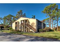Two-story condo building with a wood staircase and screened-in patio at 19 Quails Run Blvd # 2, Englewood, FL 34223