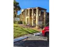 Exterior view of condo building with parking and landscaping at 26 Quails Run Blvd # 7, Englewood, FL 34223