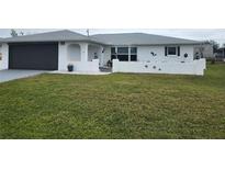 Charming single-story home features a well-manicured lawn, attached garage, and a decorative privacy wall at 7381 Thomas St, Englewood, FL 34224