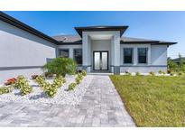 Modern home exterior with landscaping, paver walkway, and double doors at 12004 Newgate Ave, Port Charlotte, FL 33981
