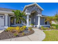 House exterior showcasing a gray house with stone accents, landscaping, and a walkway at 10083 Kansas City St, Port Charlotte, FL 33981