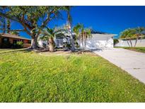 White house with a green lawn, palm trees, and a driveway at 217 Rotonda Cir, Rotonda West, FL 33947