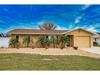 Tan house with brown roof, landscaping, and a two-car garage at 10308 Greenway Ave, Englewood, FL 34224