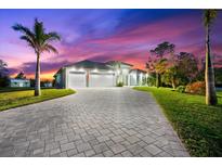 Luxury home with a large driveway and manicured lawn at sunset at 15576 Aldama Cir, Port Charlotte, FL 33981