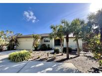Single-story home with attached garage and tropical landscaping at 3075 Bay Oaks Cir, Englewood, FL 34223